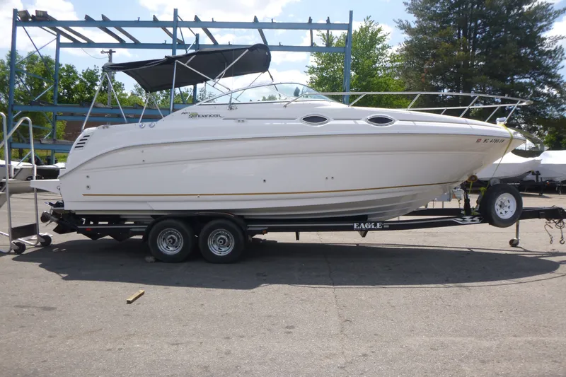 The Image of 2002 Sea Ray Sundancer 260 boat on trailer, parked outdoors under a clear sky. - 1