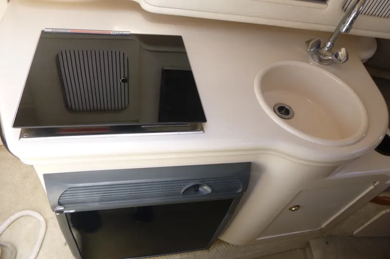Slide: The Image of 2002 Sea Ray Sundancer 260 galley with sink, stove, and compact refrigerator. - 10