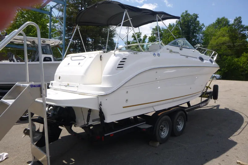 Slide: The Image of 2002 Sea Ray Sundancer 260 boat on trailer, parked outdoors under a clear sky. - 2