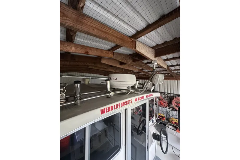 Slide: The Image of 1999 Orca 24 boat under wooden roof, safety warnings visible. - 13