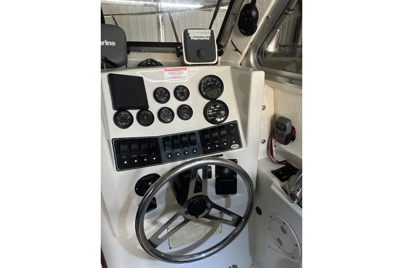 Slide: The Image of 1999 Orca 24 boat dashboard with steering wheel, gauges, and control switches. - 17