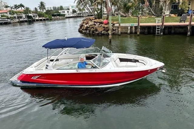 Slide: The Image of 2016 Cobalt A28 boat with red hull and blue canopy on a calm waterway. - 3