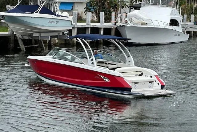Slide: The Image of 2016 Cobalt A28 boat with red hull and blue canopy on a calm waterway. - 21