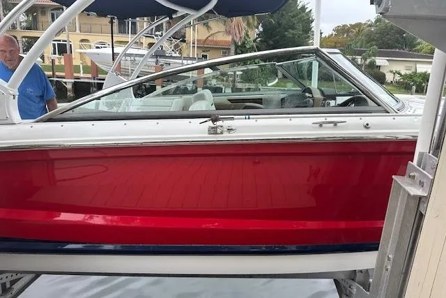 Slide: The Image of 2016 Cobalt A28 boat with red hull, docked near waterfront homes. - 16