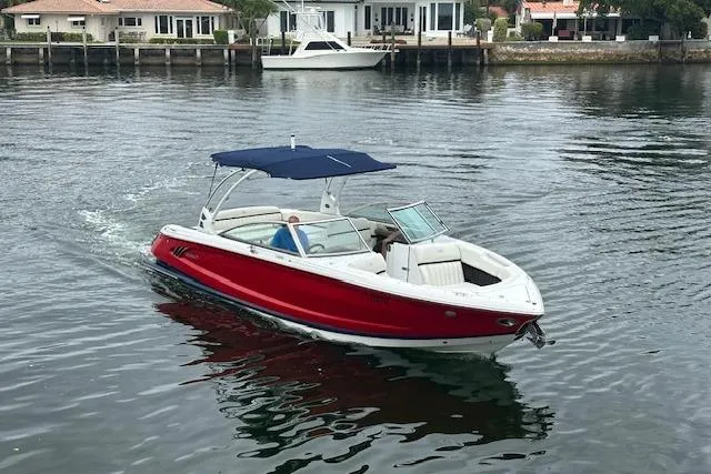Slide: The Image of 2016 Cobalt A28 boat with red hull and blue canopy cruising on calm water. - 1