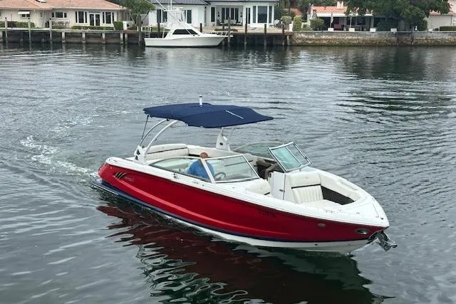 Slide: The Image of 2016 Cobalt A28 boat with red hull and blue canopy cruising on calm water. - 2