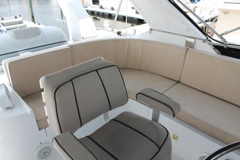 Slide: The Image of 1997 McKinna 48 Pilothouse interior with cushioned seating and helm chair, docked at marina. - 54