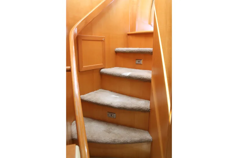 Slide: The Image of Carpeted stairs inside a 1997 McKinna 48 Pilothouse yacht with wooden railings. - 46