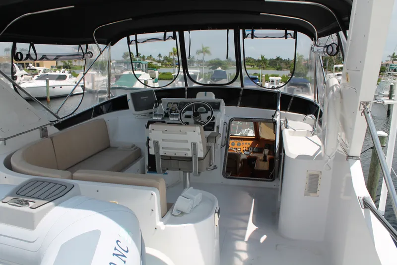 Slide: The Image of 1997 McKinna 48 Pilothouse yacht interior with helm, seating, and marina view. - 49