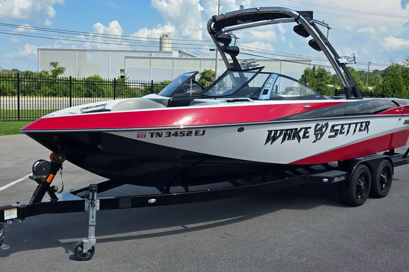 Slide: The Image of 2011 Malibu Wakesetter 247 LSV boat on trailer, red and white design, parked outdoors. - 1