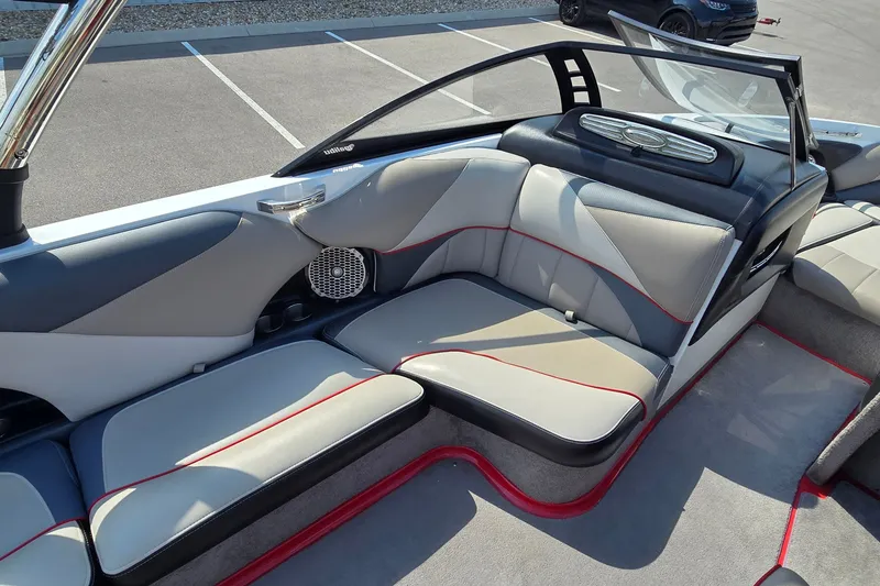 Slide: The Image of 2011 Malibu Wakesetter 247 LSV interior with gray and red-trimmed seating in a parking lot. - 11