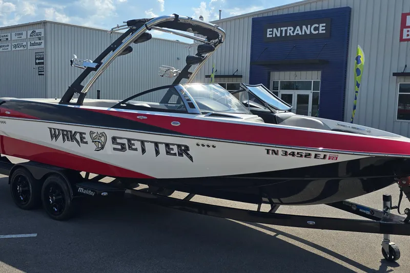 Slide: The Image of 2011 Malibu Wakesetter 247 LSV boat in red and white, parked outside dealership. - 4