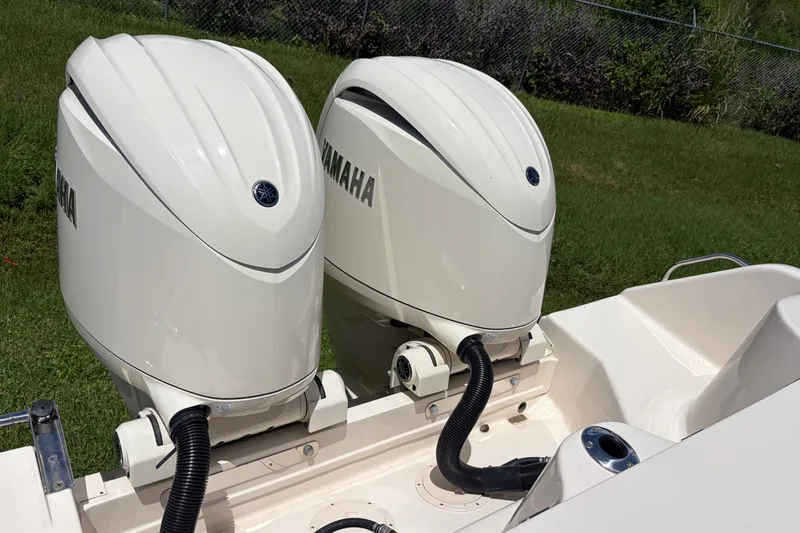 Slide: The Image of Twin Yamaha outboard engines on a 2025 Grady-White Freedom 275 boat, parked on grass. - 2