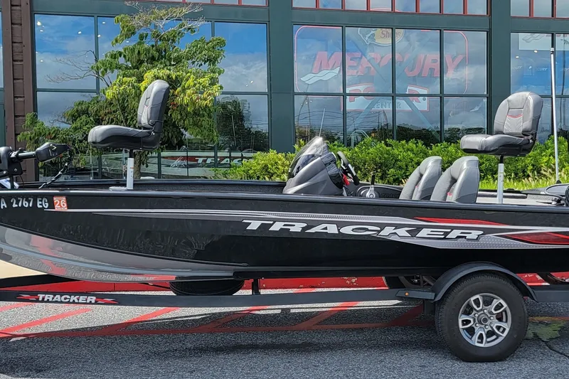 The Image of 2024 Tracker Pro Team 190 TX boat on trailer, parked outside showroom. - 1
