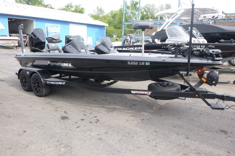 The Image of 2025 Phoenix 920 Elite boat on trailer, parked outdoors near blue building. - 1