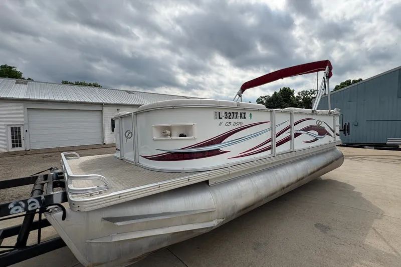 Slide: The Image of 2008 Crest 20 II pontoon boat with red accents, parked outdoors under cloudy skies. - 7