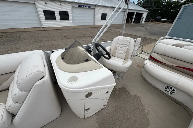 Slide: The Image of Pontoon boat interior with white seating, steering console, and showroom in background. Crest 20 II, 2008 model. - 18