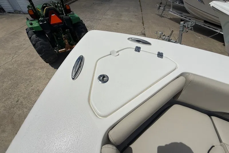 Slide: The Image of 2027 Key West 249 FS boat deck with storage hatch and seating, parked near a tractor. - 22