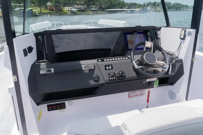 Slide: The Image of 2026 Axopar 29 XC Cross Cabin helm with modern controls and steering wheel on a lake. - 14