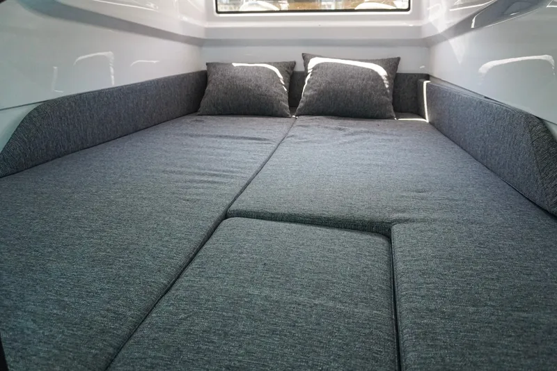 Slide: The Image of Cozy cabin interior of 2026 Axopar 29 XC Cross Cabin with gray bedding and pillows. - 13