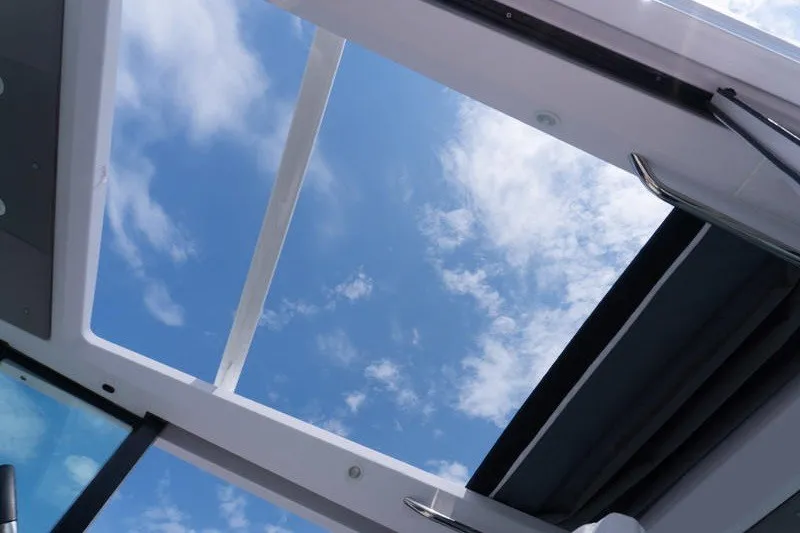 Slide: The Image of Open sunroof view from 2026 Axopar 29 XC Cross Cabin, showcasing blue sky and clouds. - 17