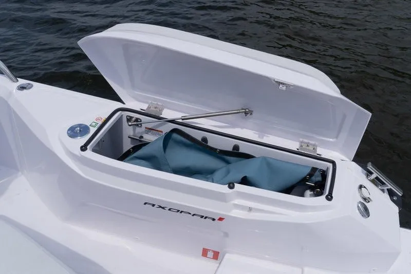 Slide: The Image of Open storage compartment on 2026 Axopar 29 XC Cross Cabin boat by the water. - 21