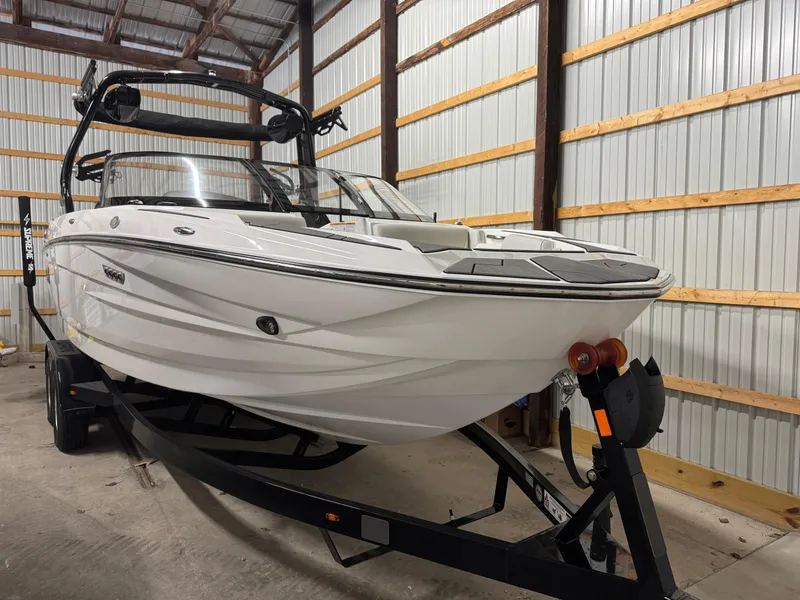 Slide: The Image of 2025 Supreme S220 boat in storage, white hull, on trailer, indoor warehouse setting. - 7