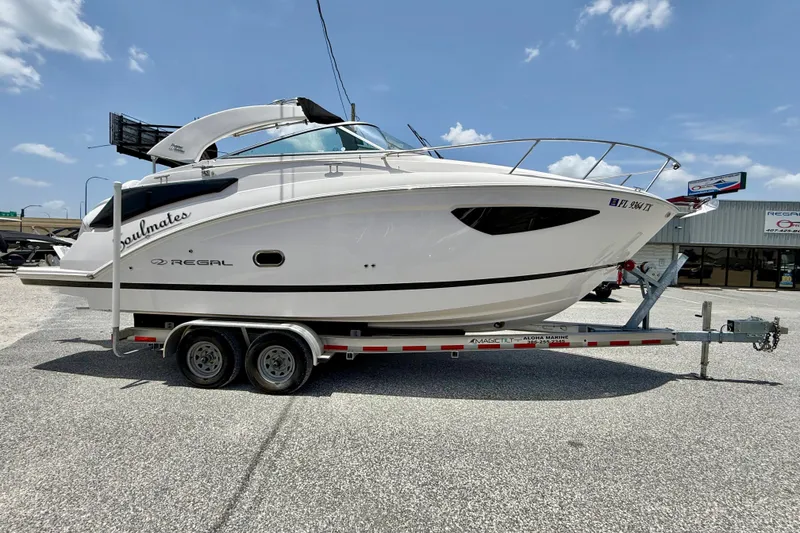 The Image of 2025 Regal 26 XO boat on trailer, displayed outdoors under a clear blue sky. - 1