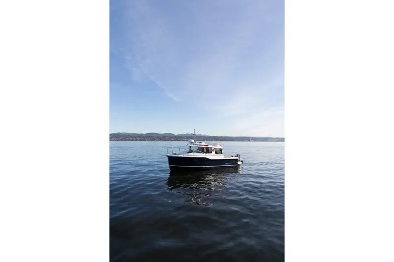 Slide: The Image of 2027 Ranger Tugs R-23 boat on calm water under clear blue sky. - 20