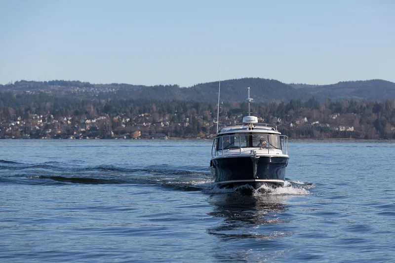 Slide: The Image of 2027 Ranger Tugs R-23 cruising on a serene lake with scenic mountain backdrop. - 3