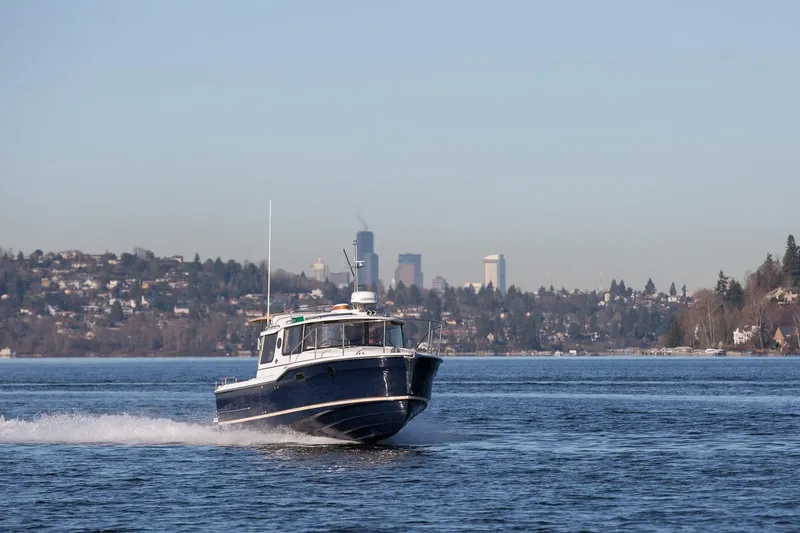 Slide: The Image of 2027 Ranger Tugs R-23 cruising on a scenic lake with city skyline backdrop. - 21