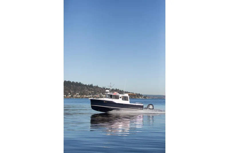 Slide: The Image of 2027 Ranger Tugs R-23 cruising on a calm lake under a clear blue sky. - 22