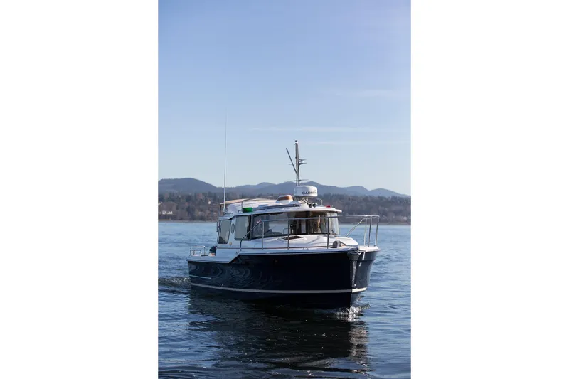 Slide: The Image of 2027 Ranger Tugs R-23 boat cruising on a calm lake with mountains in the background. - 5