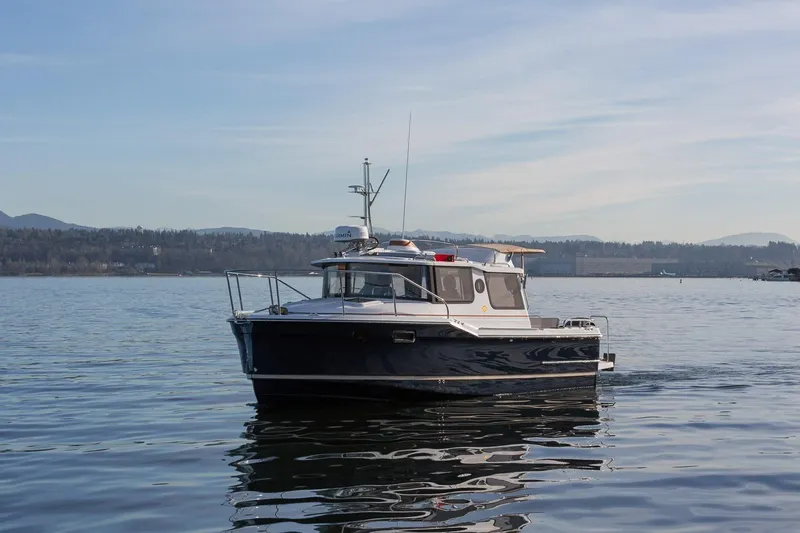 Slide: The Image of 2027 Ranger Tugs R-23 boat cruising on a calm lake with scenic mountain backdrop. - 4