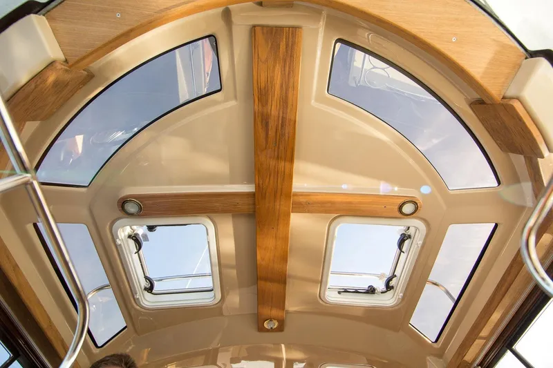 Slide: The Image of Interior view of 2027 Ranger Tugs R-23 boat ceiling with wood accents and windows. - 17