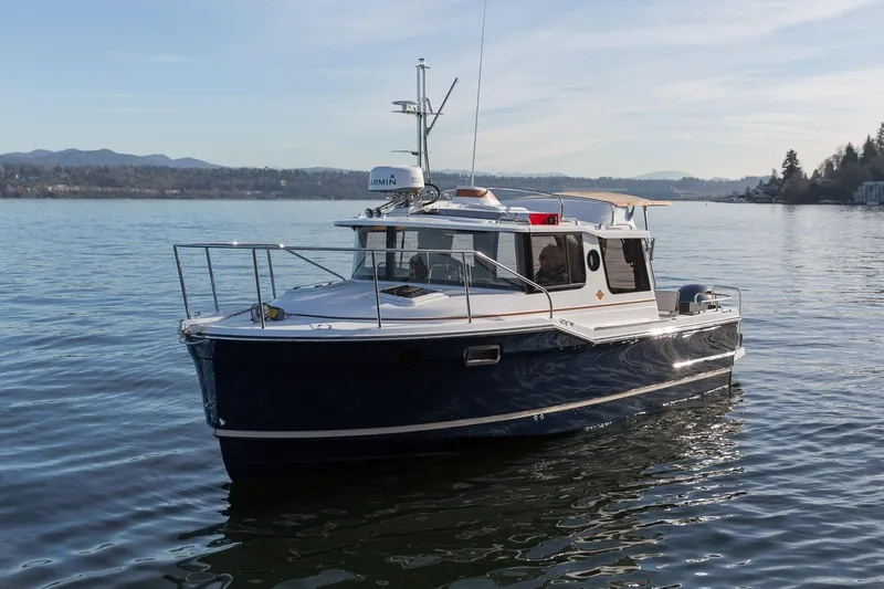 Slide: The Image of 2027 Ranger Tugs R-23 boat cruising on a calm lake with scenic mountain backdrop. - 6