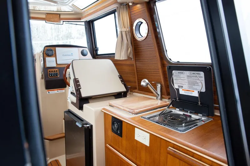 Slide: The Image of Interior of 2027 Ranger Tugs R-23 boat with helm, kitchenette, and wood finish. - 14