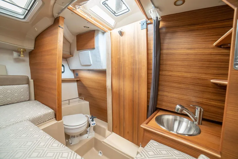 Slide: The Image of 2027 Ranger Tugs R-23 interior with wood finish, featuring a compact bathroom and sink. - 12