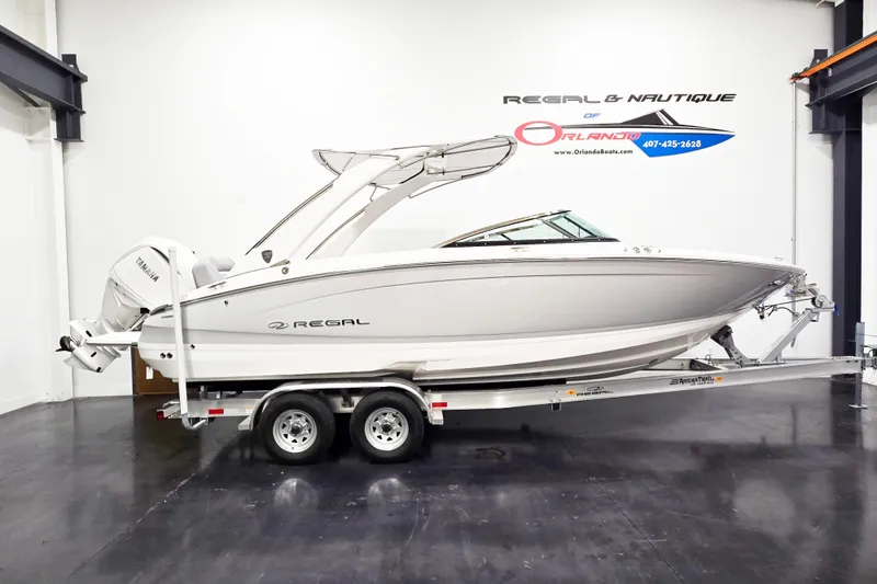 The Image of The image shows a 2027 Regal LX6 boat on a trailer in a showroom. - 1