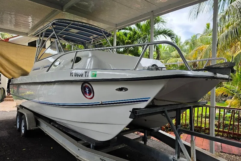 Slide: The Image of 2006 Twin Vee 26 Express boat on trailer, under shelter, surrounded by tropical foliage. - 3