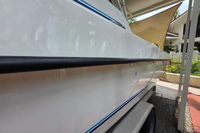 Slide: The Image of 2006 Twin Vee 26 Express boat side view, showcasing sleek white hull and blue accents. - 12