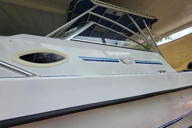Slide: The Image of 2006 Twin Vee 26 Express boat with sleek design and blue accents under a canopy. - 10