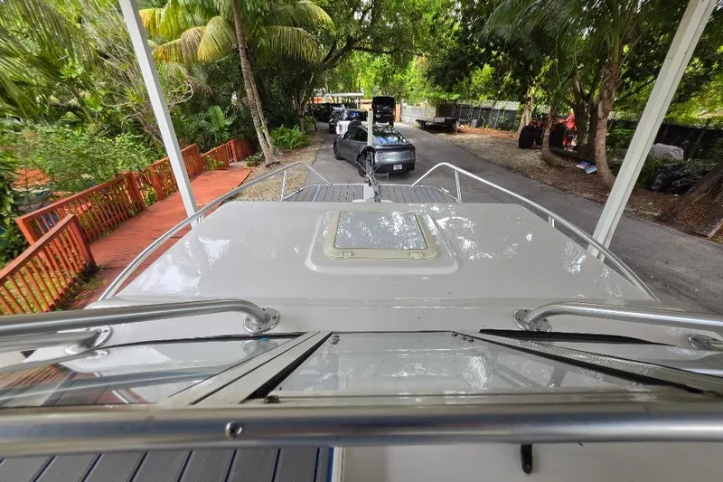 Slide: The Image of 2006 Twin Vee 26 Express boat docked, surrounded by lush greenery and parked cars. - 23