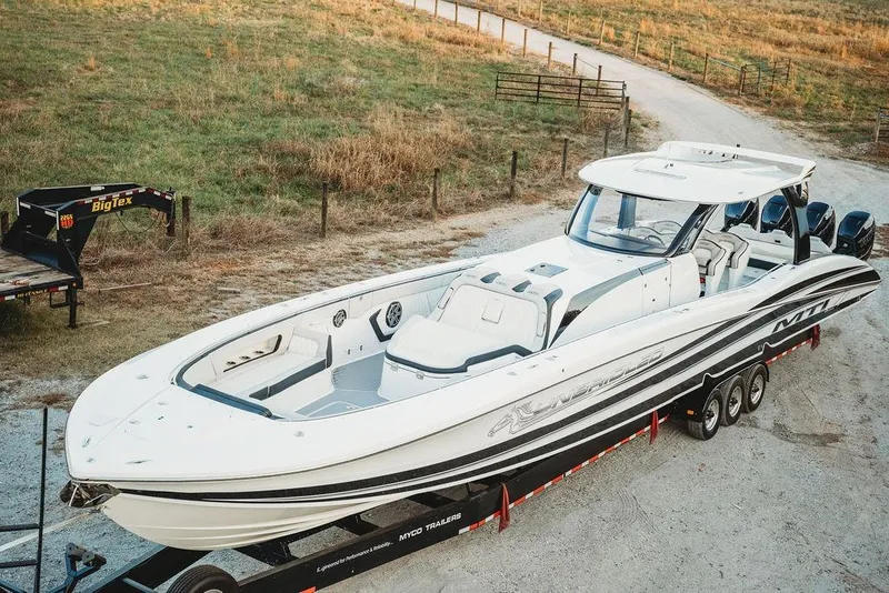 Slide: The Image of 2018 MTI 57 boat on trailer, parked on gravel road near grassy field. - 19
