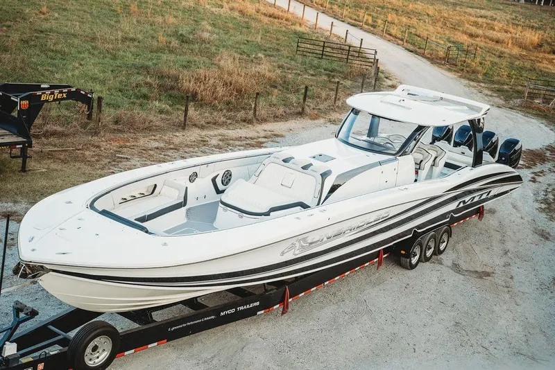 Slide: The Image of 2018 MTI 57 boat on trailer, parked on a rural dirt road. - 20