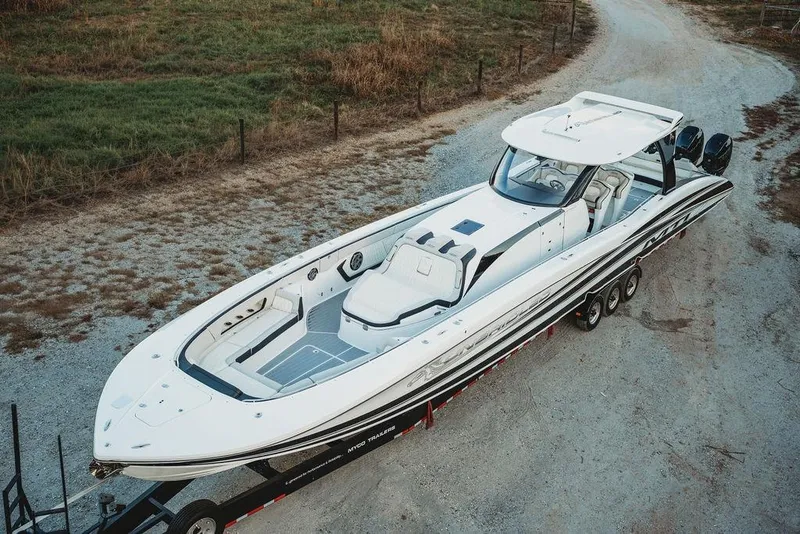Slide: The Image of 2018 MTI 57 boat on trailer, parked on gravel road, surrounded by grass. - 22