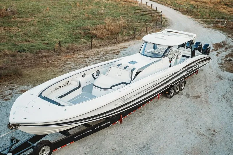 Slide: The Image of 2018 MTI 57 boat on trailer, parked on gravel road, surrounded by grass. - 21