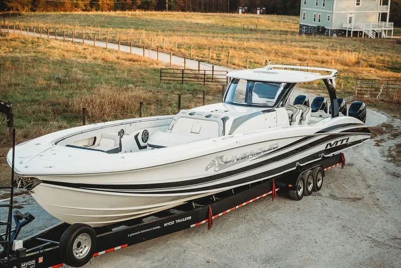 Slide: The Image of 2018 MTI 57 boat on trailer in rural setting, showcasing sleek design and powerful engines. - 17