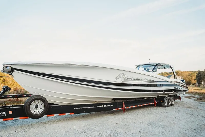 Slide: The Image of 2018 MTI 57 boat on trailer, sleek design, outdoors, clear sky background. - 8