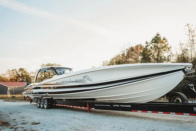 Slide: The Image of 2018 MTI 57 boat on trailer, parked outdoors, showcasing sleek design and branding. - 15